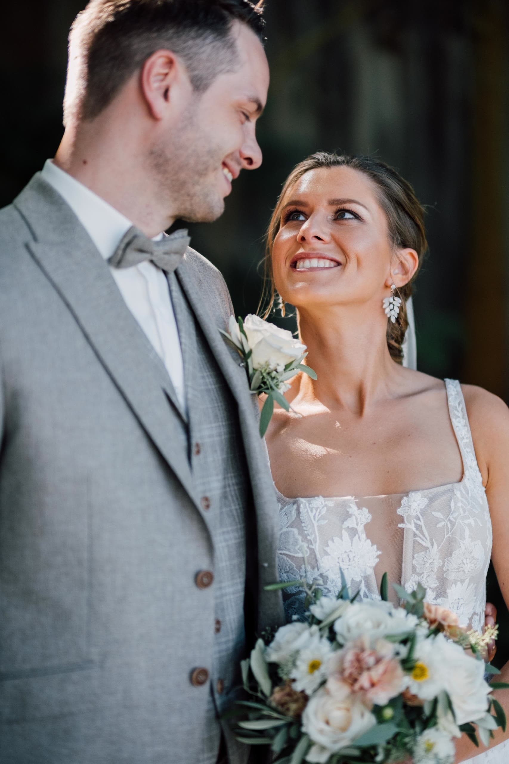 Bride looks up at the groom and laughs, her bouquet held between them