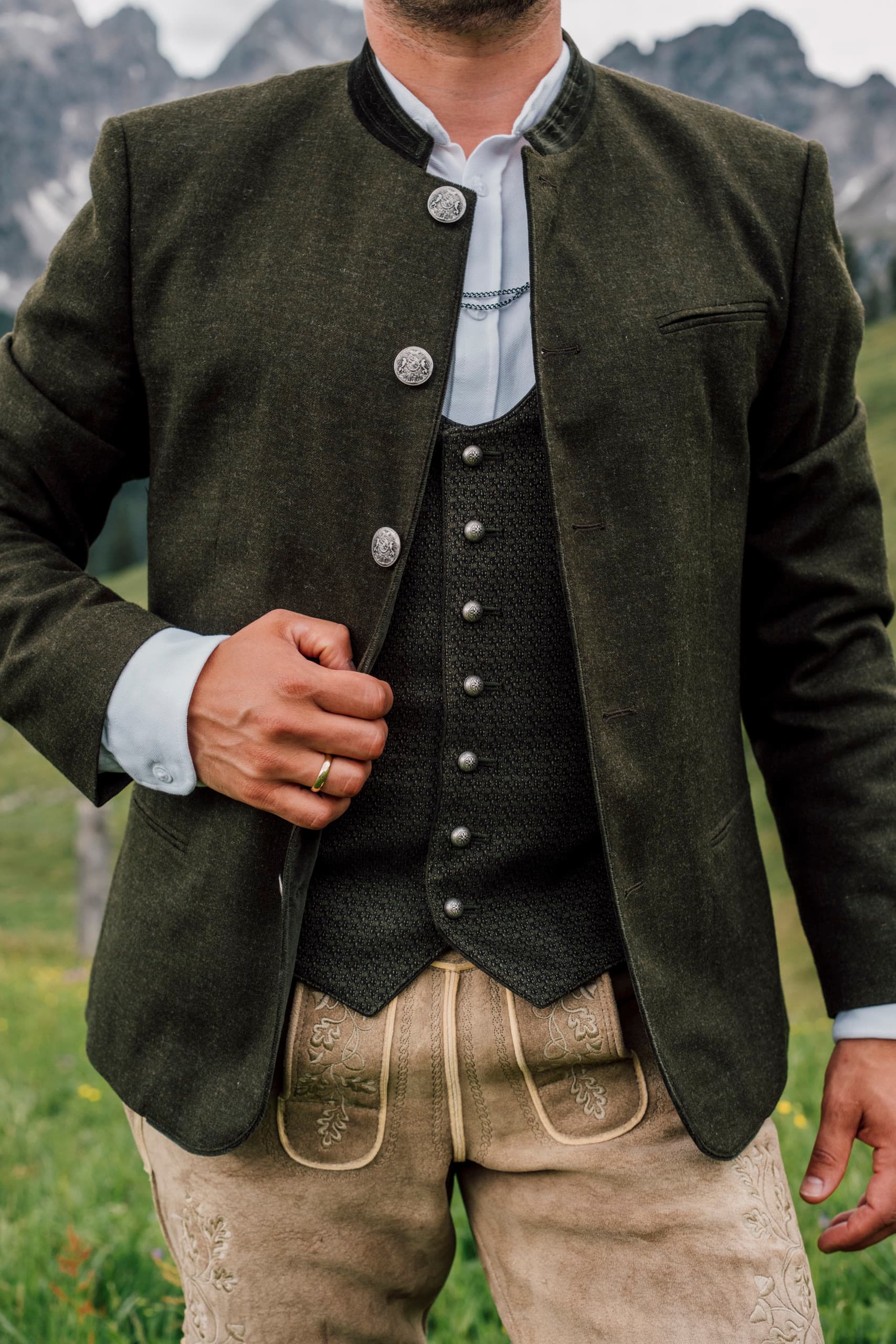 Close-up of a traditional Austrian Tracht jacket with silver buttons, mountains behind