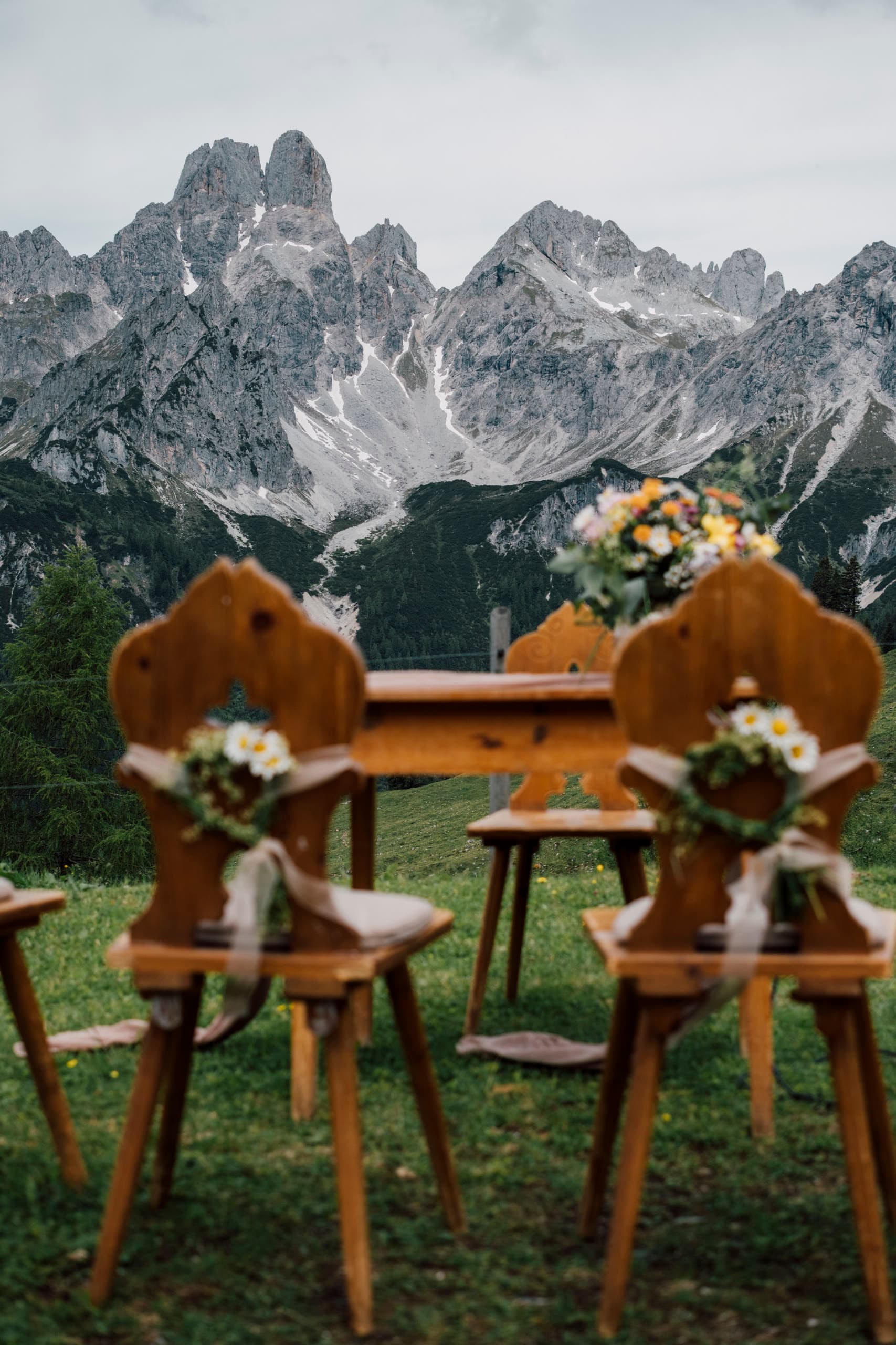 Two wooden chairs and a small table dressed with white flowers face distant mountain peaks
